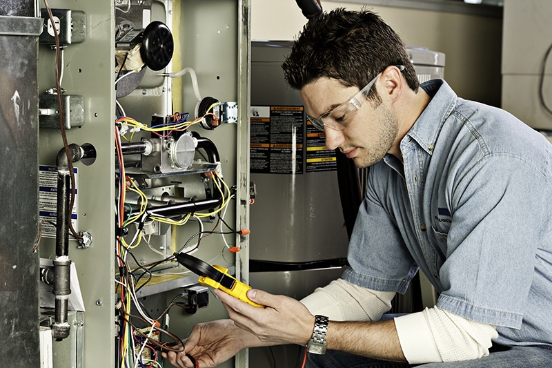 Blog Title: Why Do I Need AC Maintenance Now? Photo: Maintenance Technician fixing an AC unit