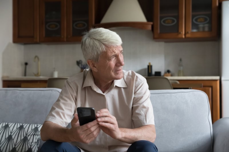 What’s That Smell Coming From My Furnace? Photo of a man sitting on his couch looking out a window, seemingly concerned.